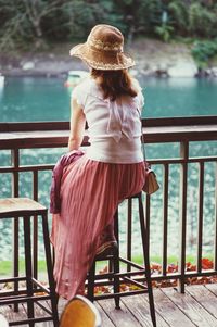 Rear view of woman sitting on railing