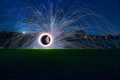 Light trails on field against sky at night