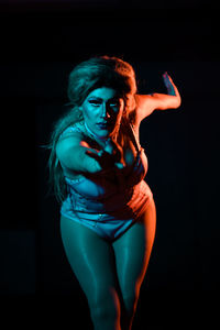 Portrait of young woman wearing mask against black background