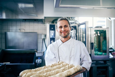 Portrait of confident chef baking breads in commercial kitchen