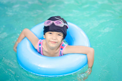 Portrait of smiling girl on inflatable ring in swimming pool