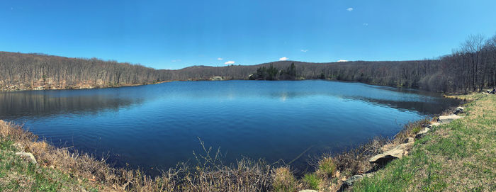 Scenic view of lake by mountains against blue sky