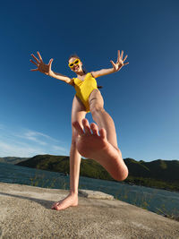Full length of young woman doing yoga against sky