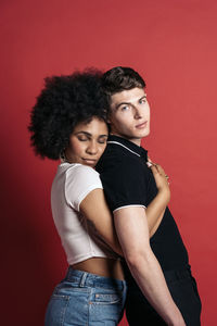 Stylish diverse girlfriend and boyfriend posing in a studio shooting with red background