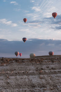 Hot air balloons flying over land against sky