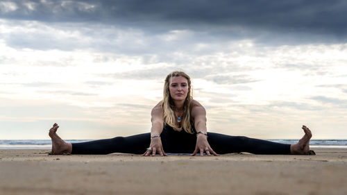 Young woman practicing yoga on the beach in newborough, north wales, uk