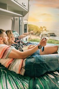 Couple watching a movie on the tablet eating popcorn lying on the bed of their camper van