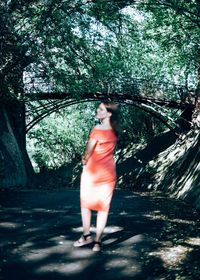 Woman standing by tree in forest