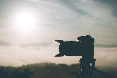 Silhouette of camera against sky during sunset