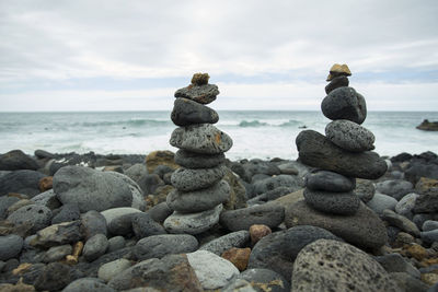 Stack of stones on beach against sky