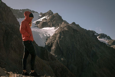 Man standing on rock by mountain against sky