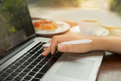 Close-up of hand using laptop on table