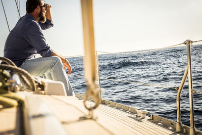 Man sitting on boat sailing in sea against sky