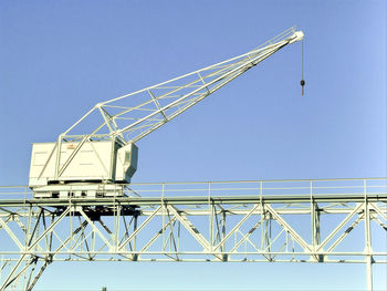 Low angle view of cranes against clear blue sky