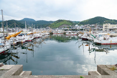 Sailboats moored at harbor against sky