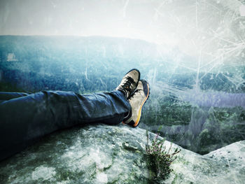 Low section of person relaxing on rock