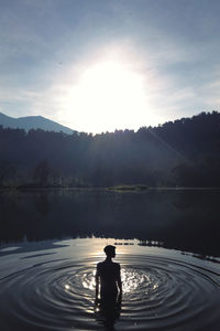 Silhouette of man on lake against sky