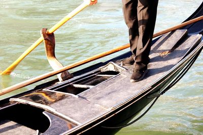 Low section of man standing on gondola over grand canal