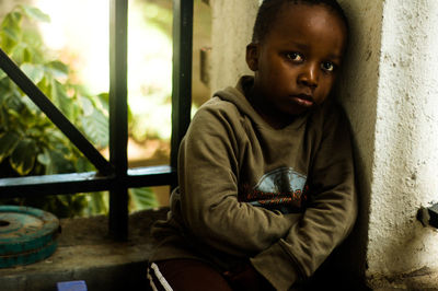 Portrait of boy sitting by wall