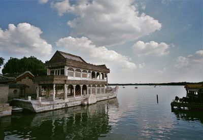 Building in lake against cloudy sky