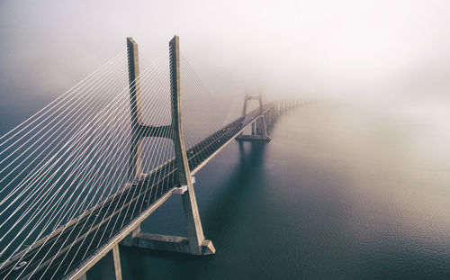 Suspension bridge over river against sky