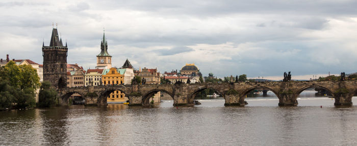 Arch bridge over river against cloudy sky