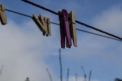 Clothespins hanging on clothesline against sky