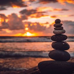 Stack of stones on beach during sunset