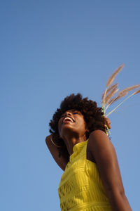 Portrait of a young black woman wearing yellow dress holding grass