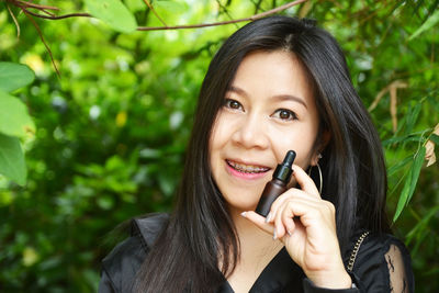 Portrait of a smiling young woman holding plant