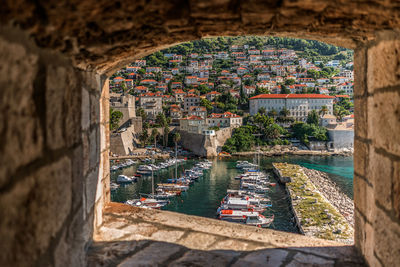 Boats moored in sea by townscape seen through window