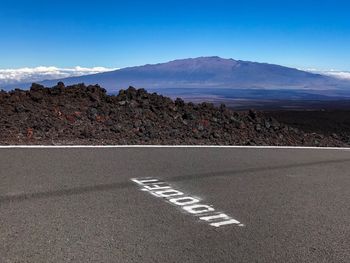 Road by mountains against sky