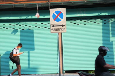 Rear view of man and woman sign against blue sky