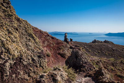 Man standing on rock by sea against sky