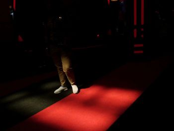 Low section of woman walking on illuminated street