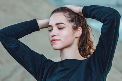 Graceful young woman lifting her hair with both hands