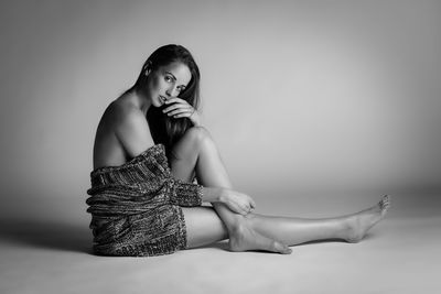 Portrait of sensuous woman sitting against gray background