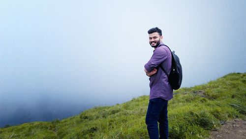Smiling man standing on mountain against sky