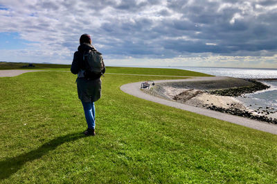 Rear view of man on grass against sky