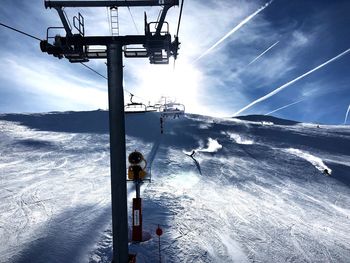 Ski lift over snow covered mountains against sky