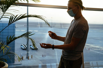 Man using sanitizer spray on hands at the airport or public place. backlight 