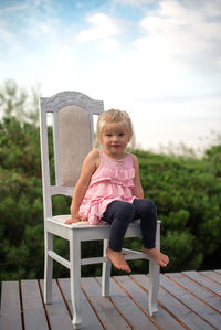 Portrait of girl sitting on chair at porch