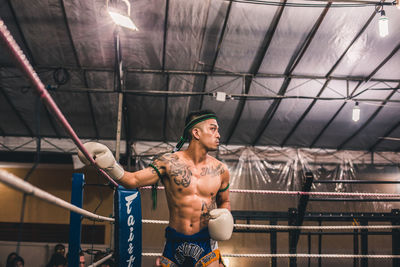 Full length of shirtless man standing against illuminated ceiling