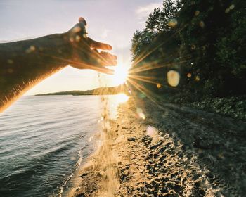 Cropped hand at beach on sunny day