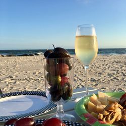 Champagne flute with cheese and olives on table at beach during sunny day