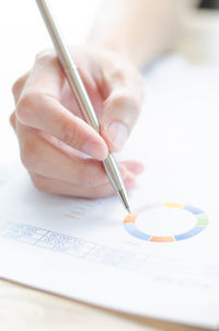 Cropped hand of businesswoman analyzing data at desk in office