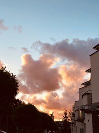 Low angle view of silhouette trees and buildings against sky