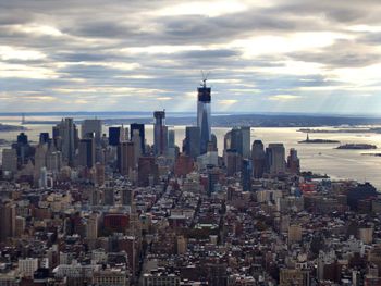 Aerial view of buildings in city against cloudy sky