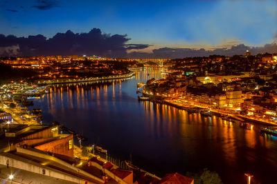 High angle view of illuminated buildings by river against sky