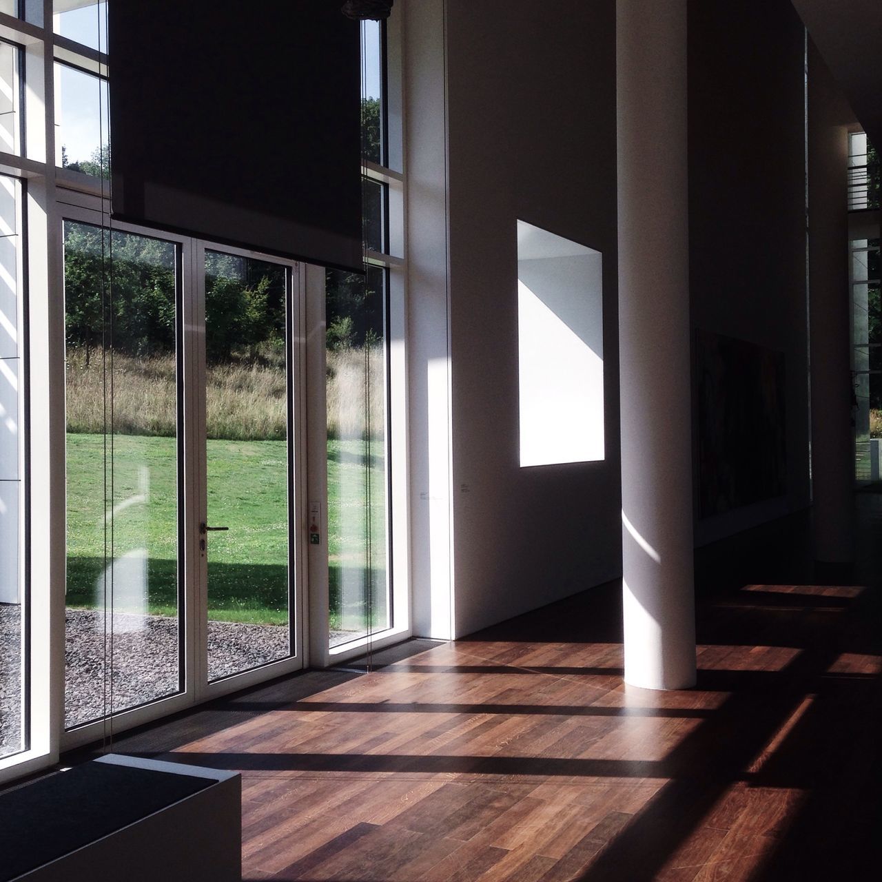 indoors, architecture, window, built structure, glass - material, transparent, flooring, architectural column, sunlight, door, corridor, empty, tiled floor, absence, column, shadow, interior, day, reflection, no people